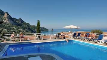 Una piscina al aire libre de temporada, sombrillas