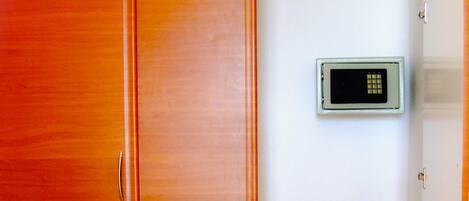 Una habitación con un armario de madera, una pared blanca y un termostato digital.