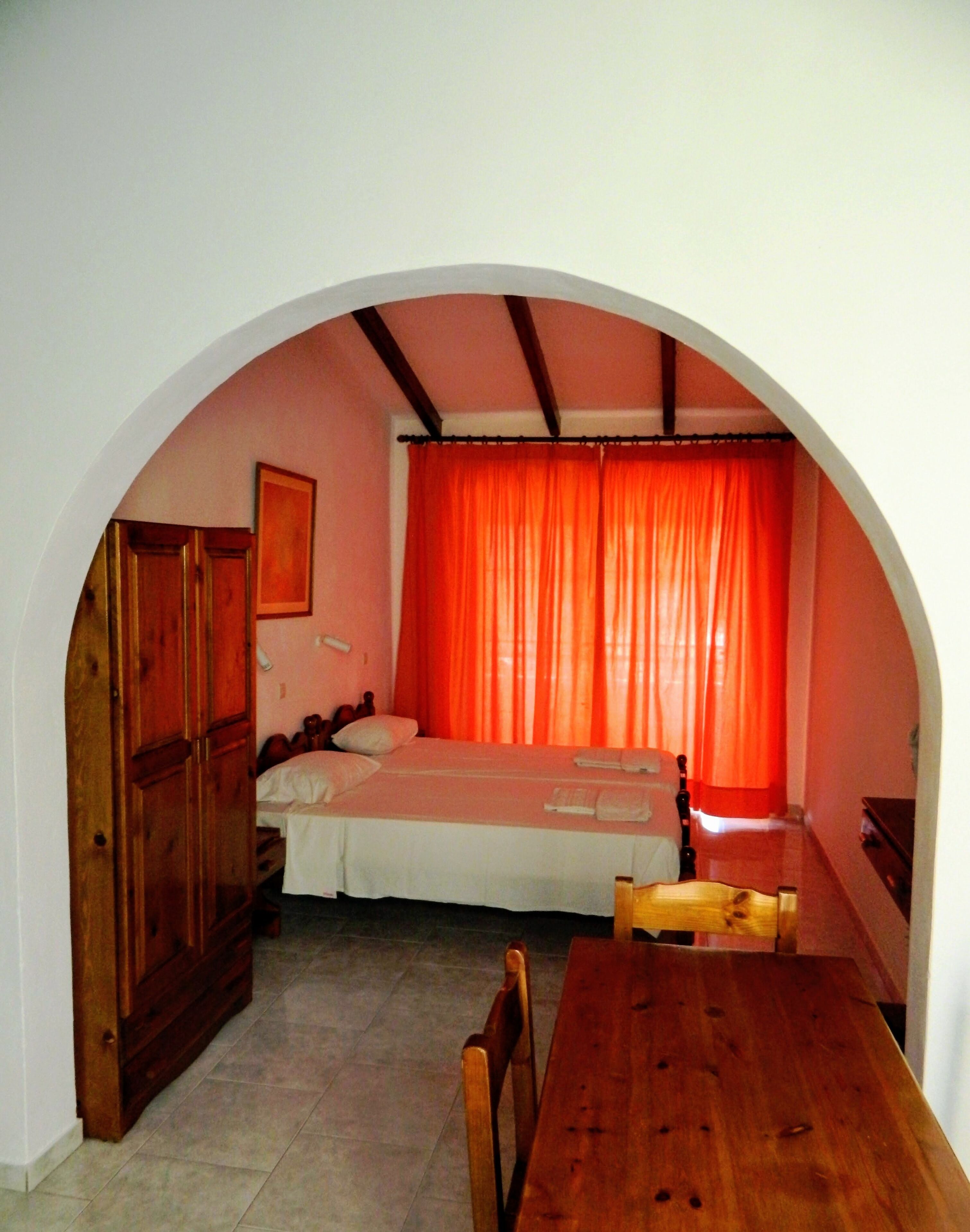 A room with a bed, a wooden table, and a wardrobe.