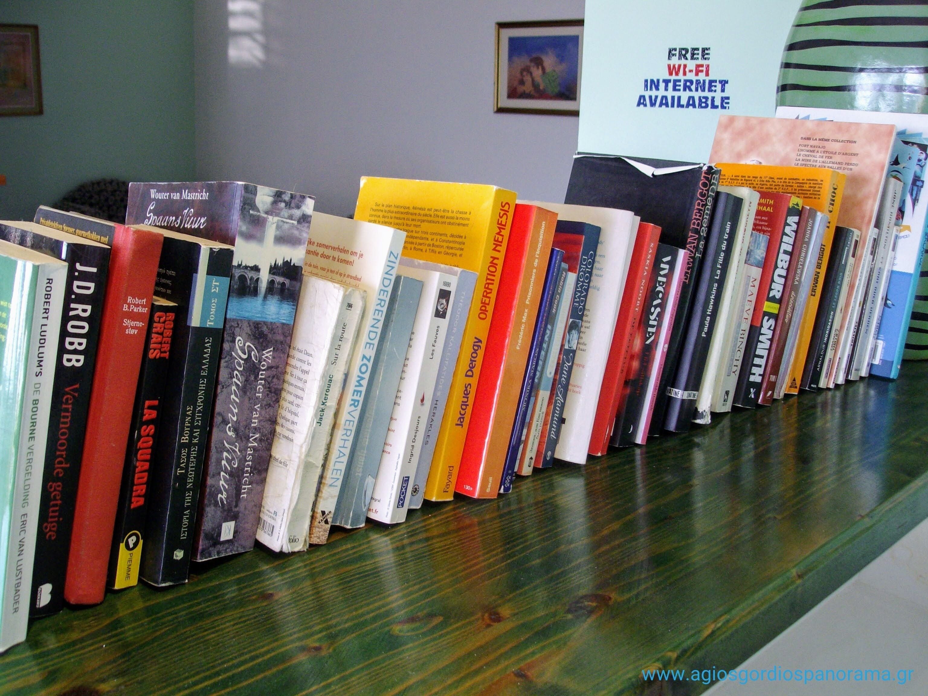 Una fila de libros en un estante con un cartel que indica conexión Wi-Fi gratuita.