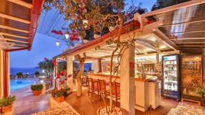 Un espace bar avec vue sur la piscine, des places assises en plein air et un comptoir.