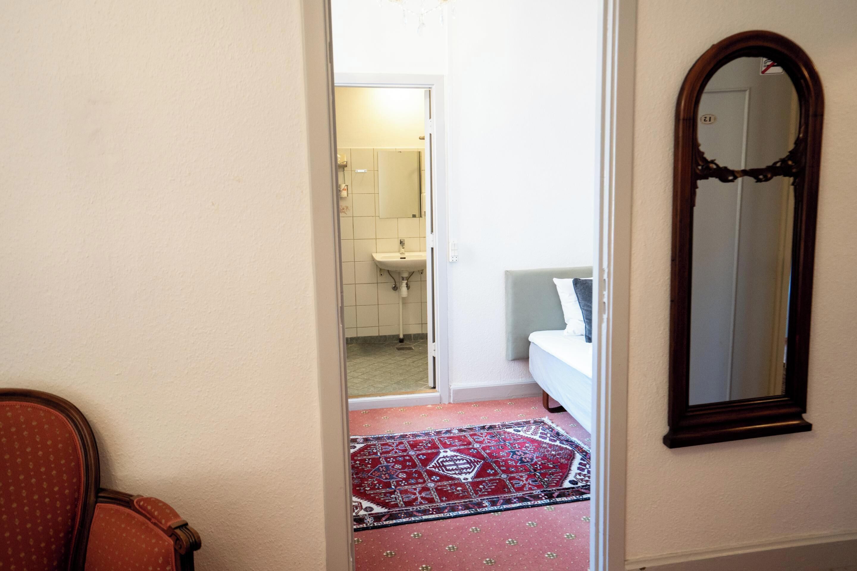 Un pasillo que da a un baño con lavabo y espejo.