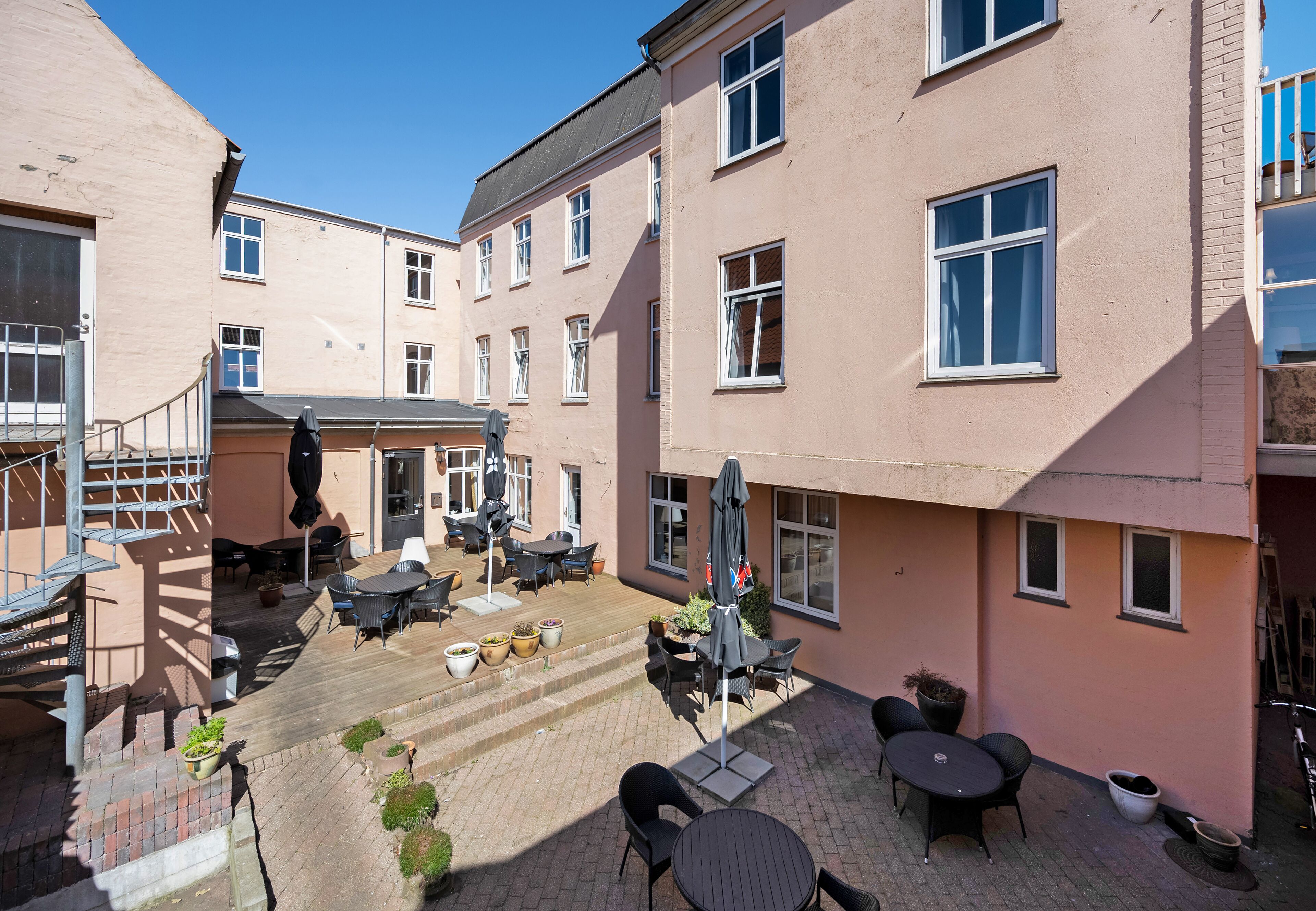A courtyard with outdoor seating, a staircase, and a building facade.