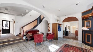 A spacious lobby with a grand staircase, red upholstered chairs, and a large patterned rug. - Hotel Postgaarden (Fredericia)