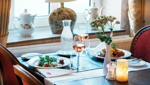 A dining table set with plates, glasses, a candle, and a vase with flowers. - Hotel Postgaarden (Fredericia)