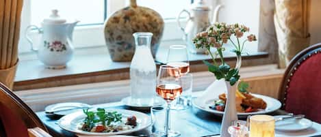 A dining table set with plates, glasses, a candle, and a vase with flowers.