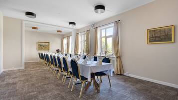 A long dining table with chairs, a white tablecloth, and a painting on the wall.
