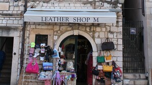 Un edificio de piedra con un cartel que dice 'LEATHER SHOP M'.
