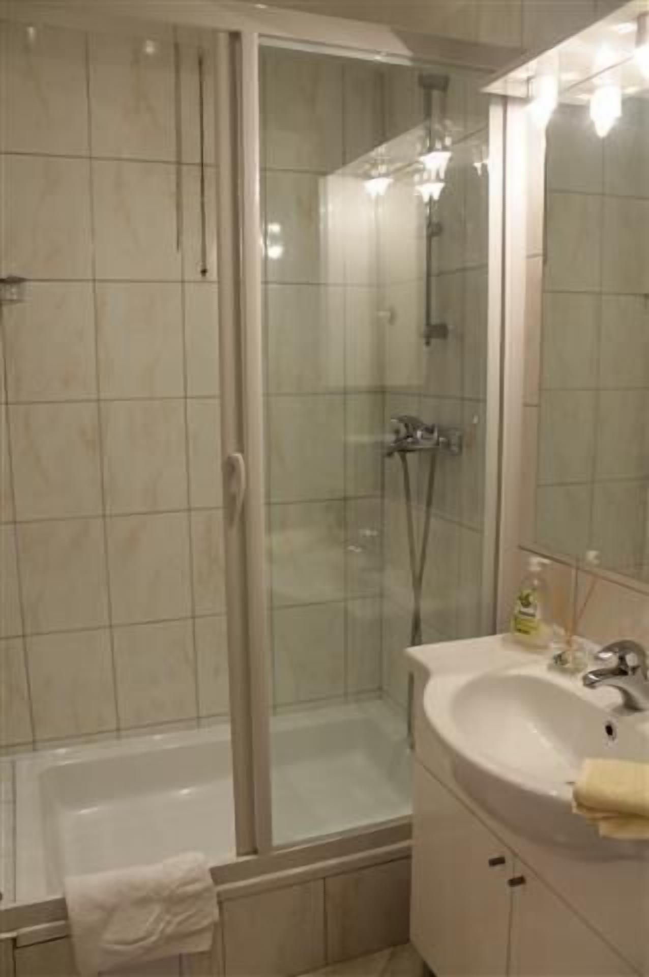 Un bagno con doccia vetrata, vasca e lavandino con specchio.