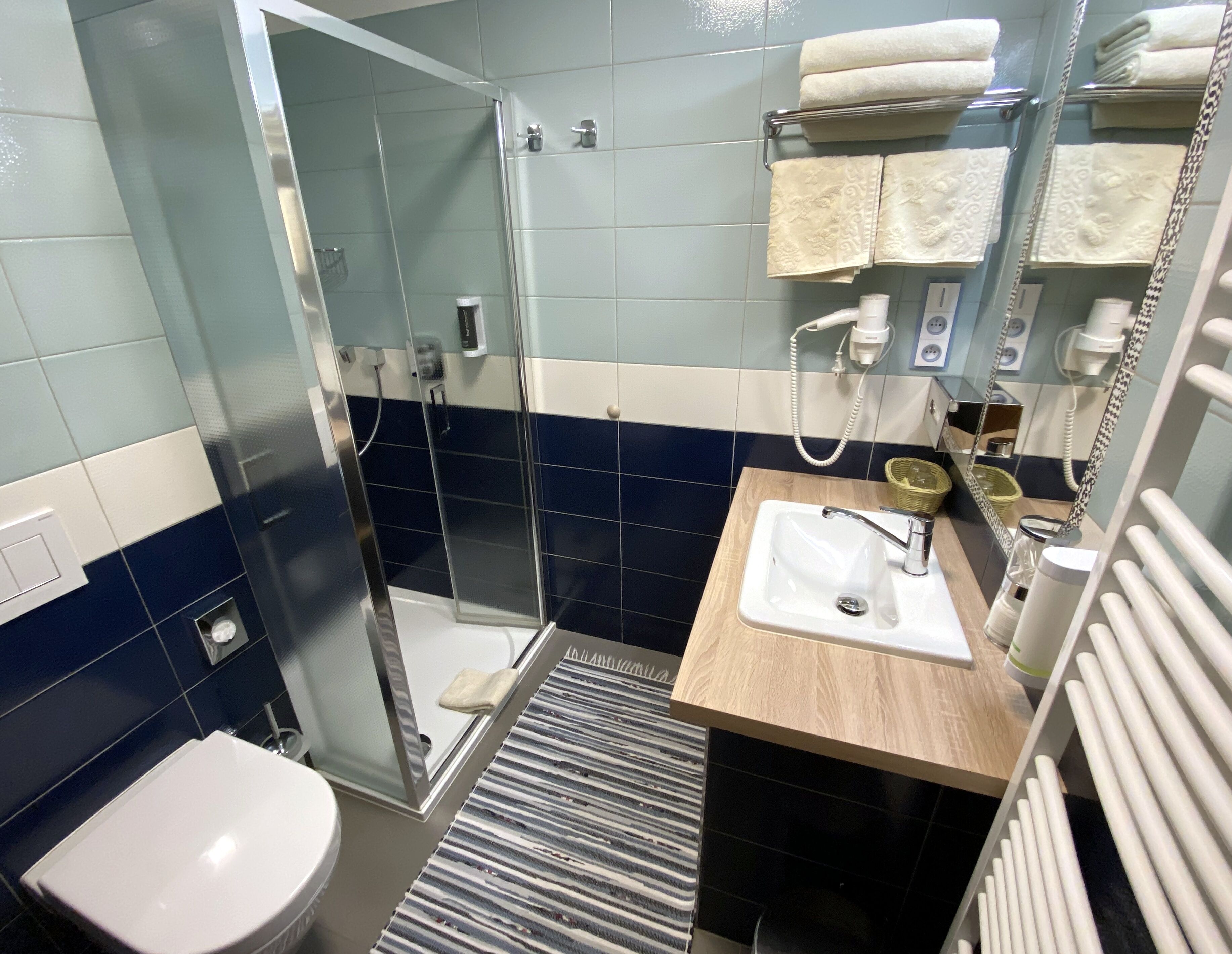 A bathroom with a shower, toilet, sink, and a mirror with towels.