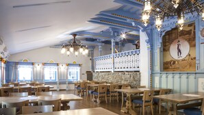 A restaurant with wooden tables and chairs, stone walls, and blue ceiling beams. - Hotel na Dolině (Trojanovice)