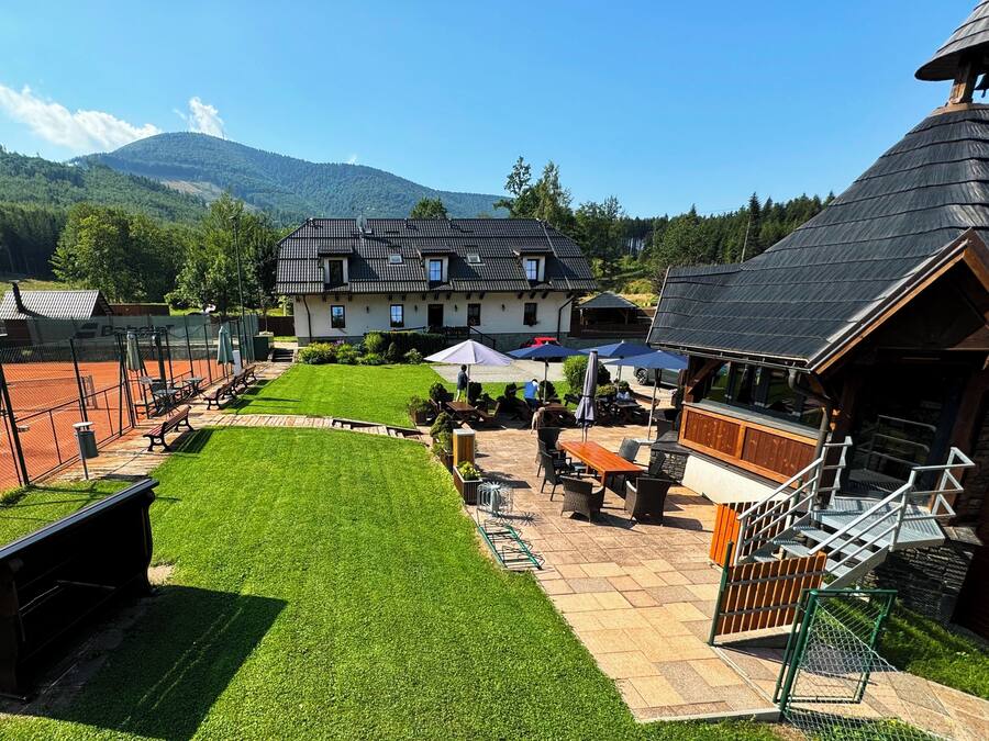A courtyard with a tennis court, outdoor seating, and a mountain backdrop.