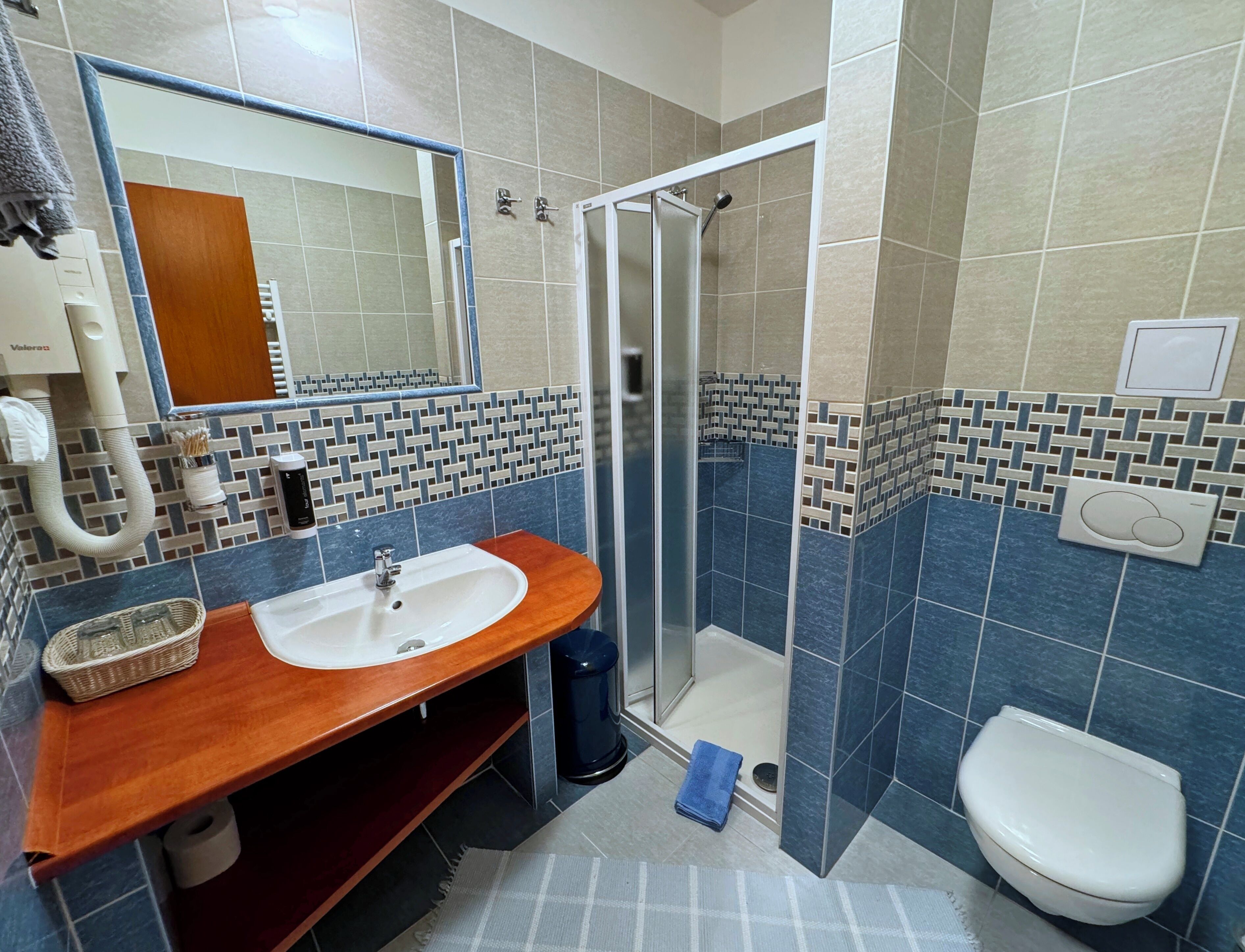 A bathroom with a wooden vanity, a sink, a mirror, a shower, and a toilet.
