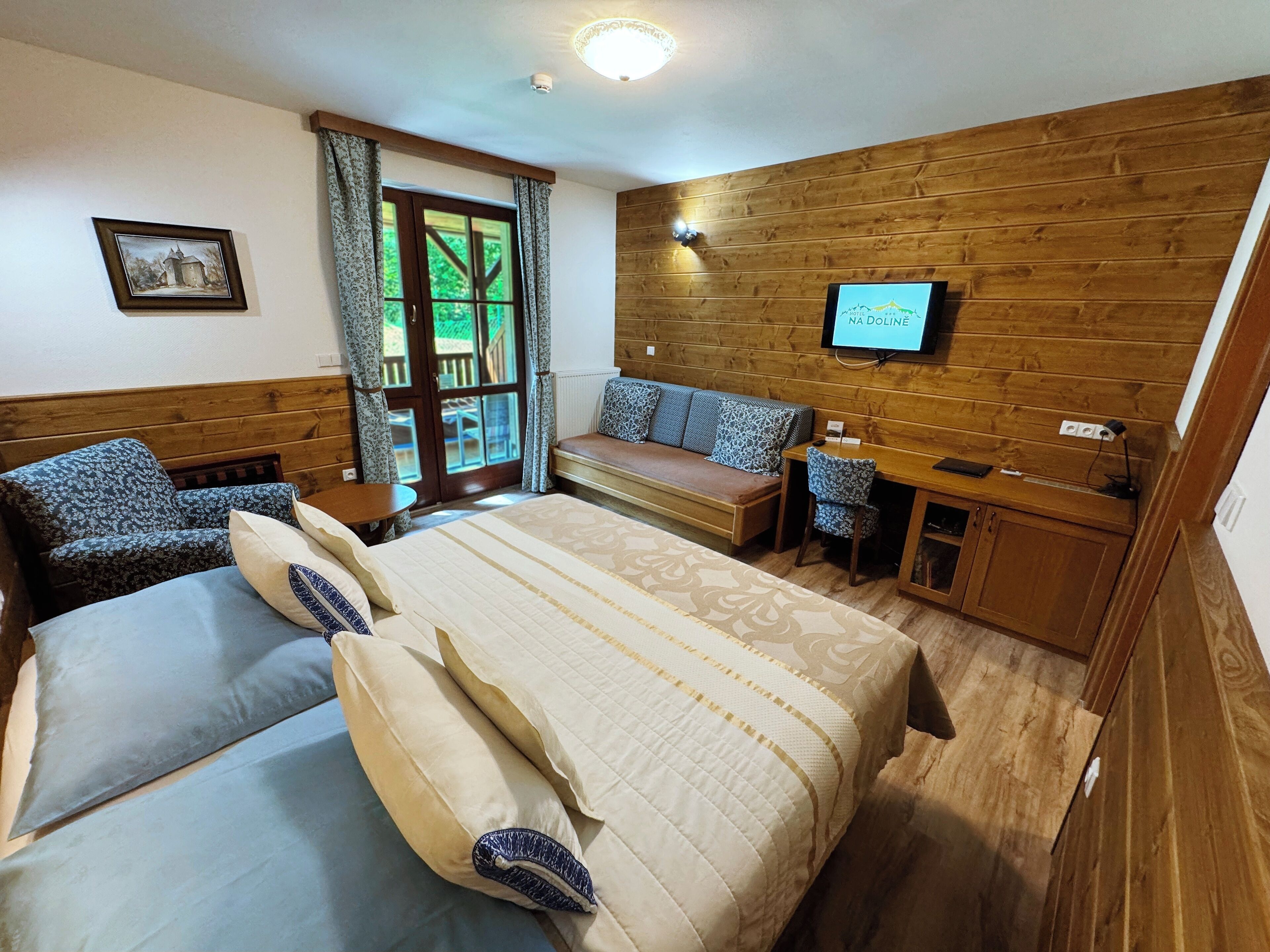 A bedroom with a bed, a sofa, a desk, and a television.