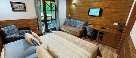 A bedroom with a bed, a sofa, a desk, and a television.