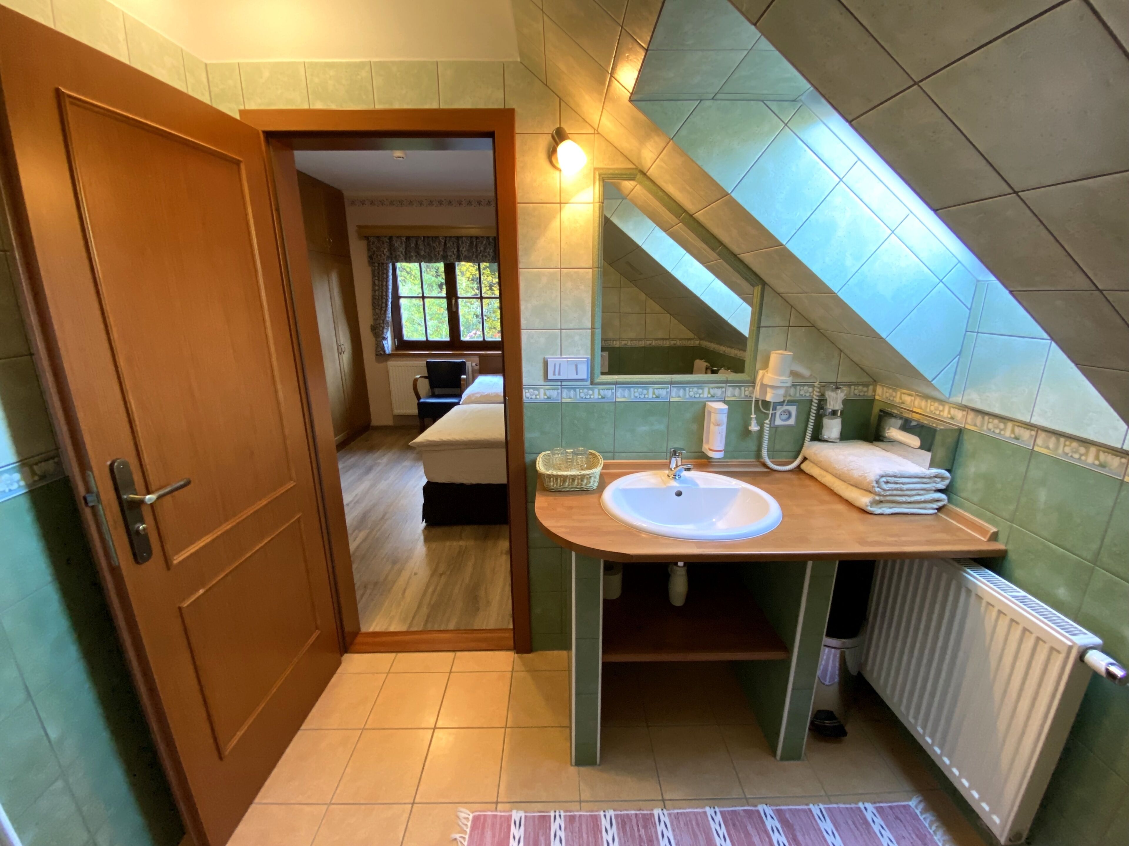 A bathroom with a wooden vanity, a sink, and a mirror. There is a window with a view of greenery outside.