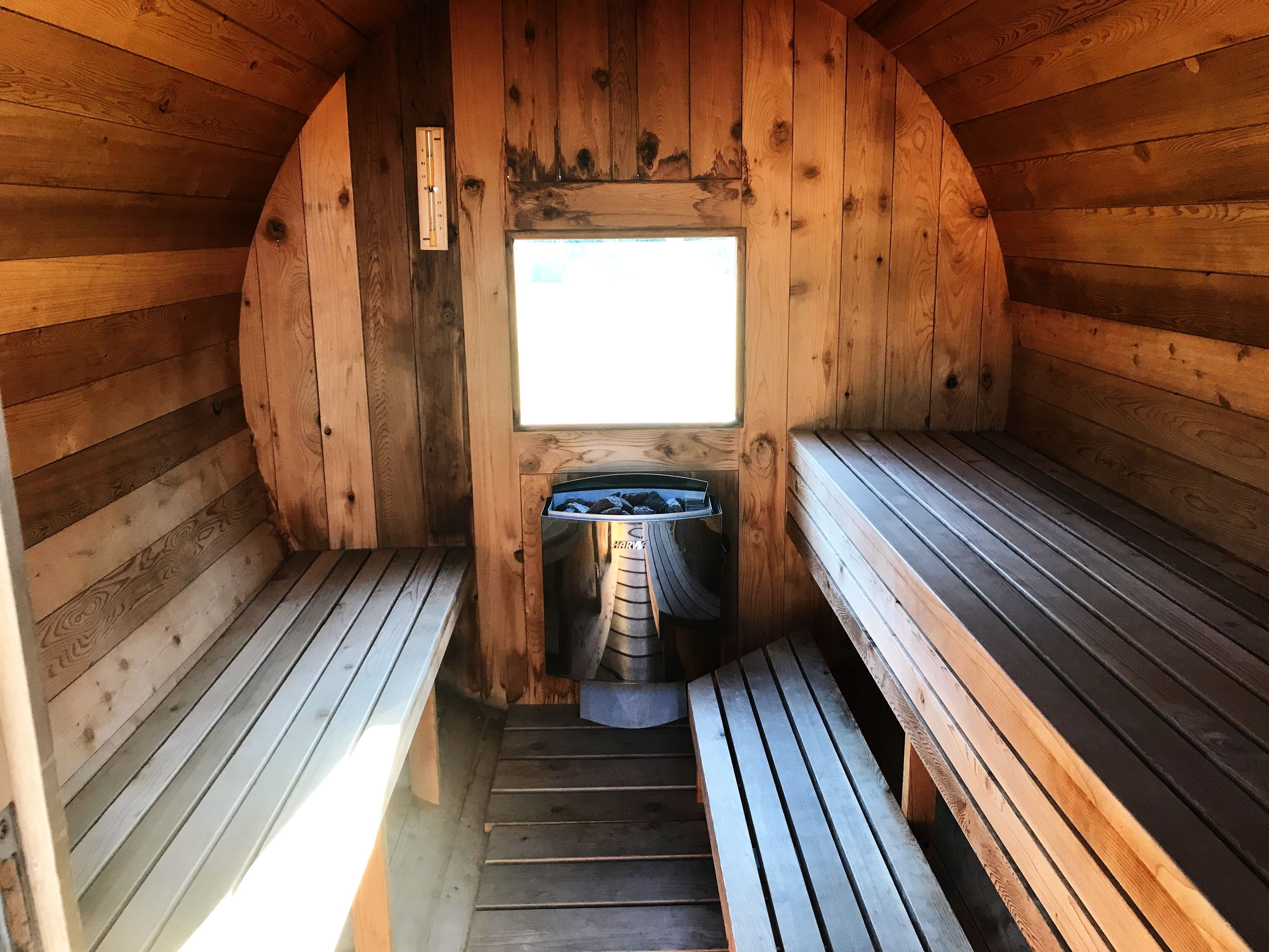 A sauna with wooden walls, benches, and a window.