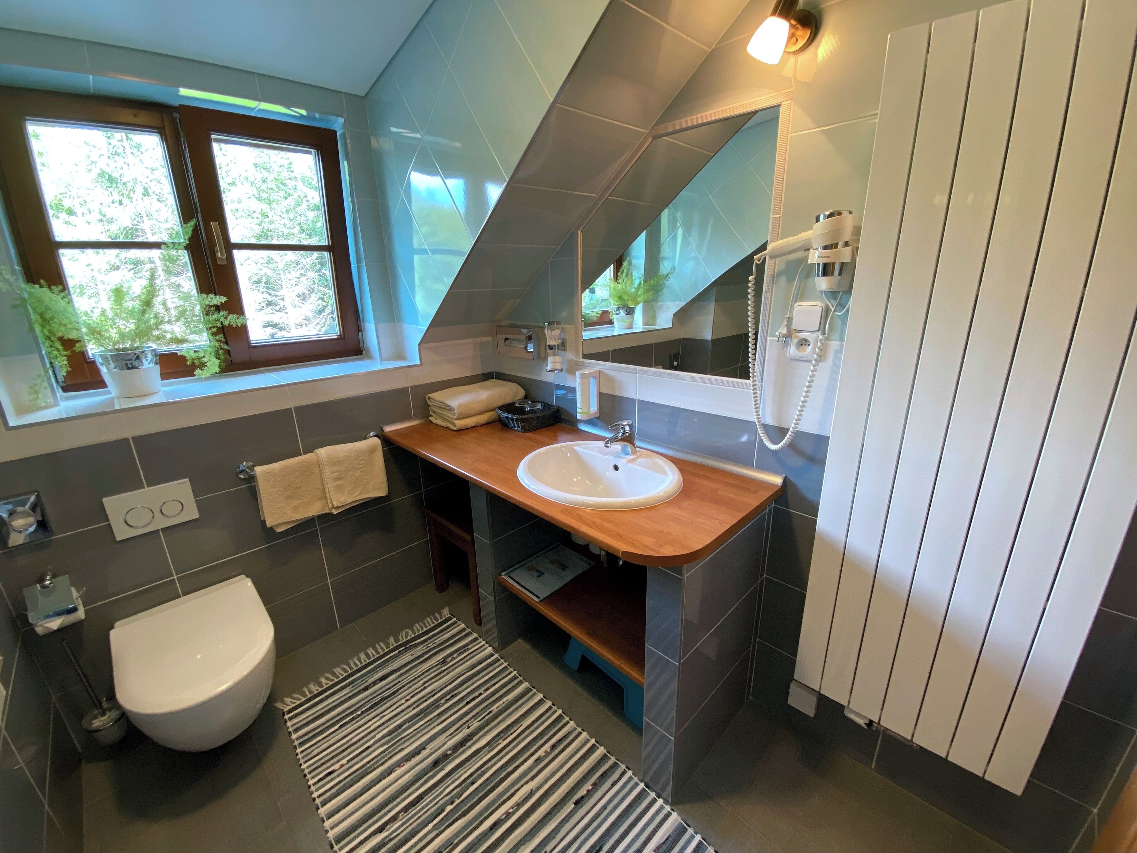 Ein modernes Badezimmer mit Fenster, Waschbecken, Toilette und Dusche.