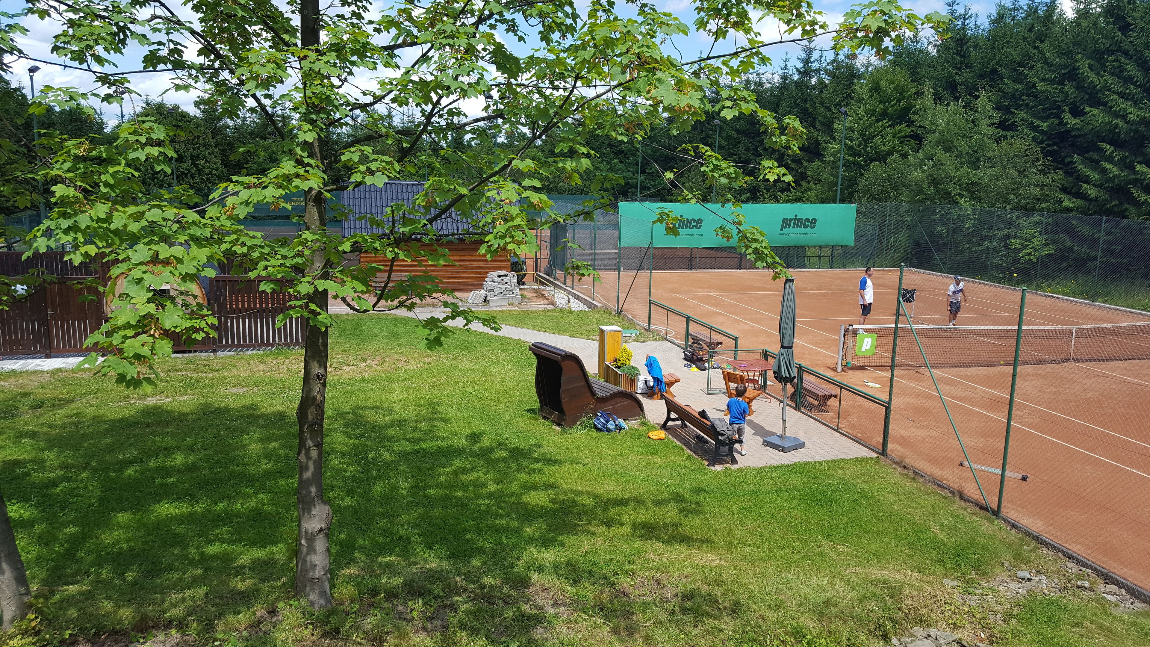 Una cancha de tenis con red, bancos y una estructura de madera.