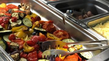 Buffet com diversos legumes cozidos e uma concha.