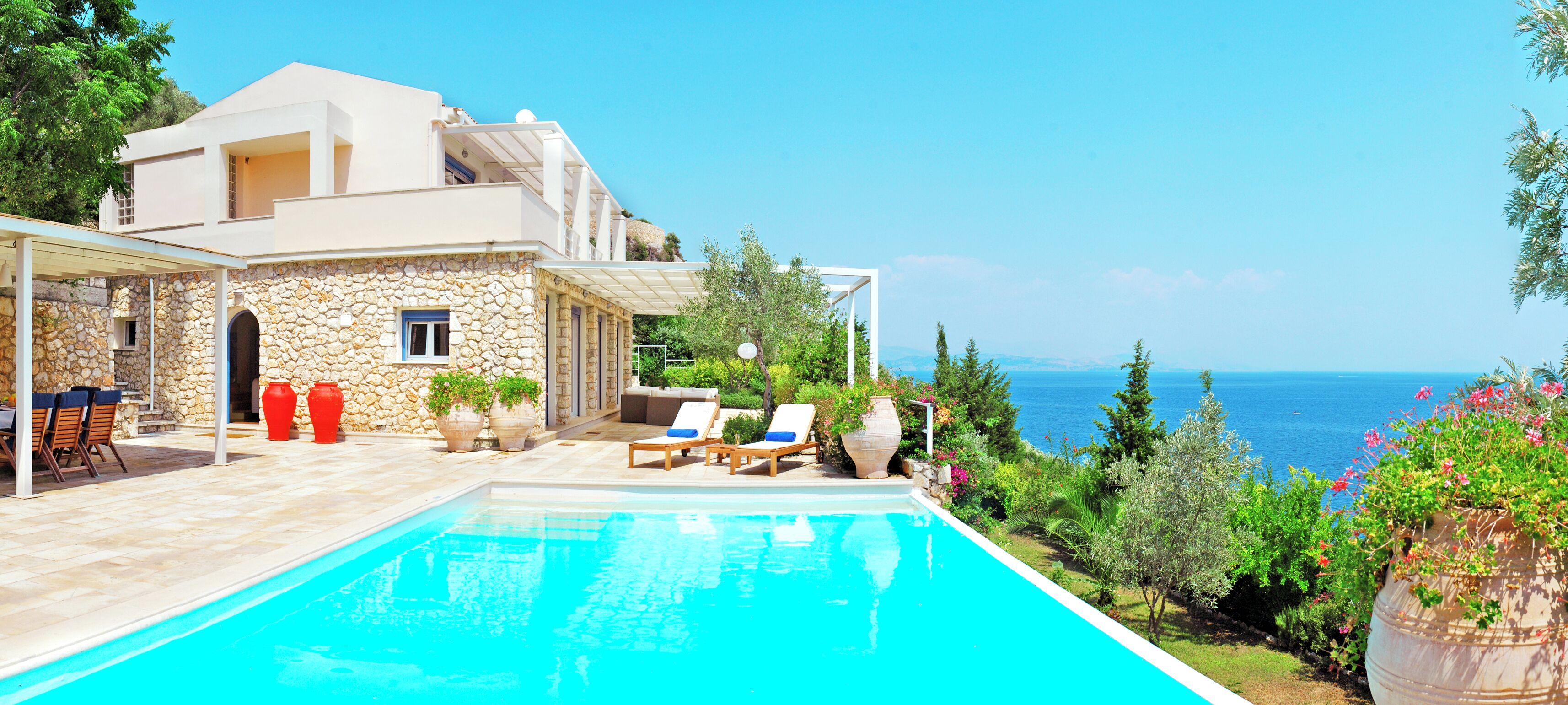 Une maison moderne dotée d’une piscine, d’un espace extérieur aménagé et offrant une vue sur la mer.