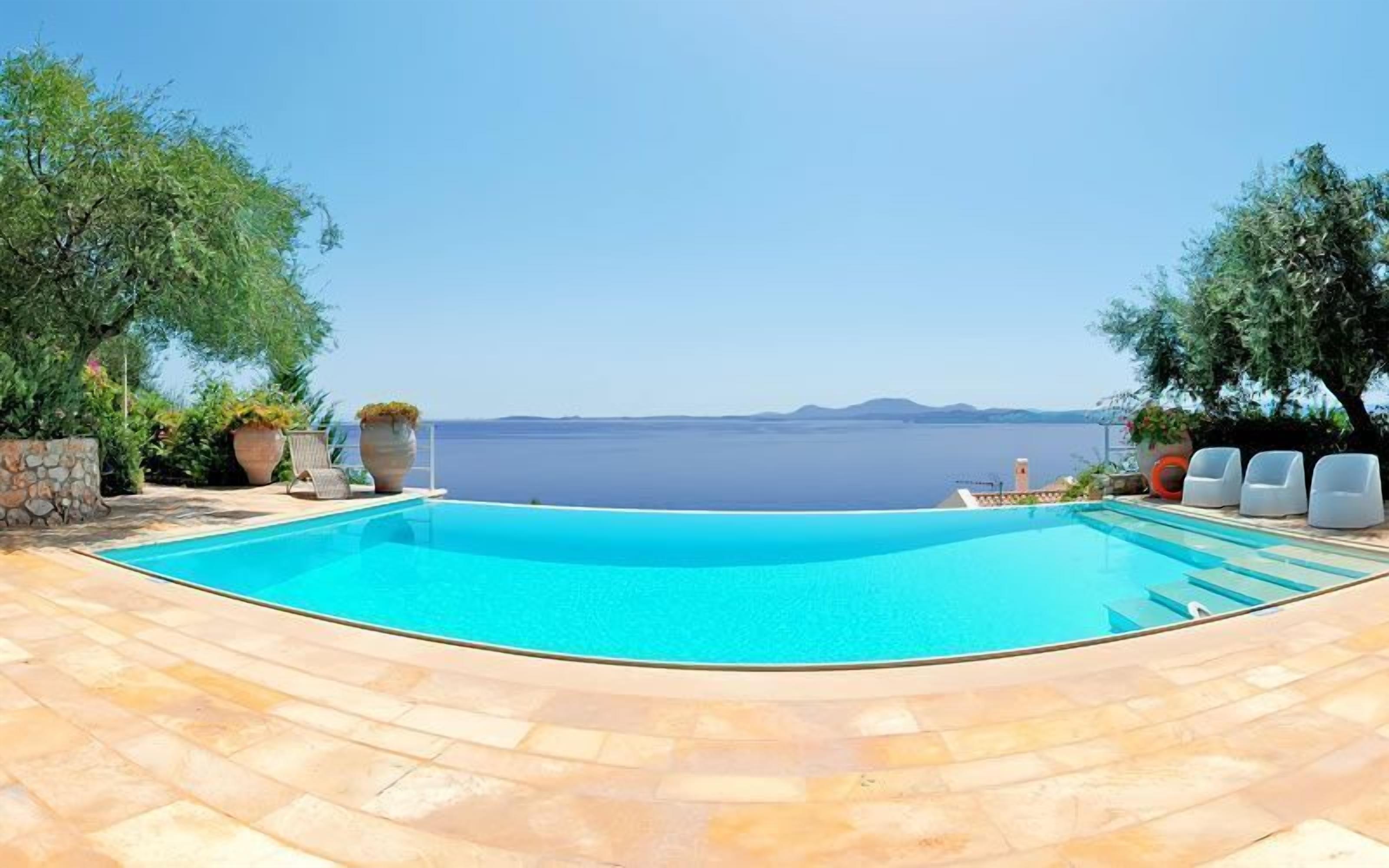 A swimming pool with a view of the sea and mountains.
