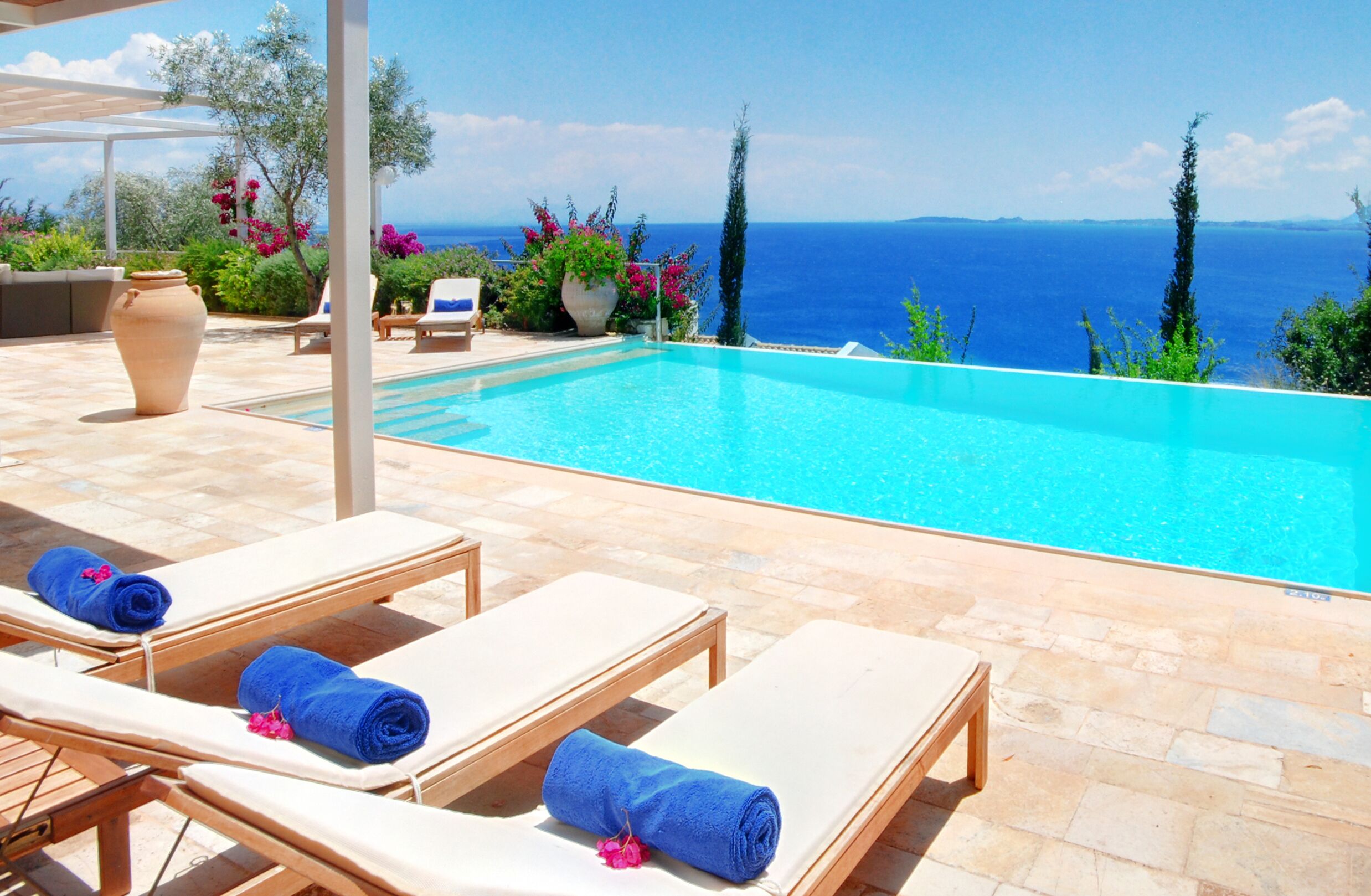 A poolside area with lounge chairs and a view of the sea.