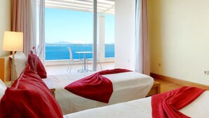 A hotel room with two beds, a table, and a chair. The room has a view of the sea and mountains. - Corfu Luxury Villas (Corfu)