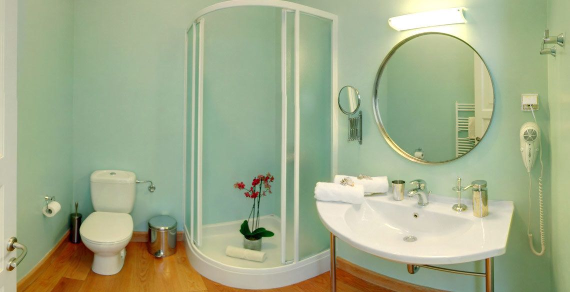 Ein Badezimmer mit Toilette, Dusche, Waschbecken und Spiegel.