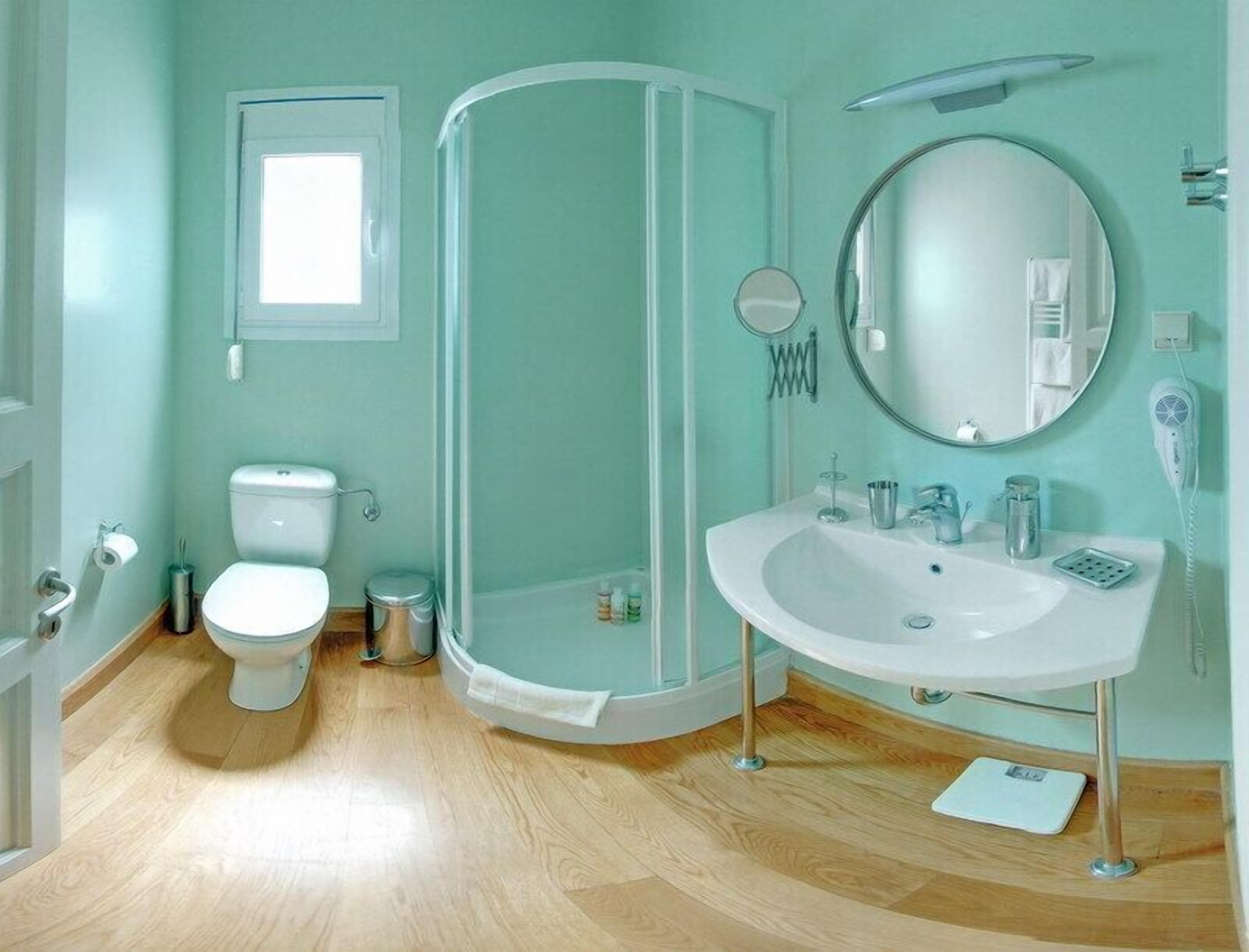 Un baño con inodoro, lavamanos, ducha y espejo.