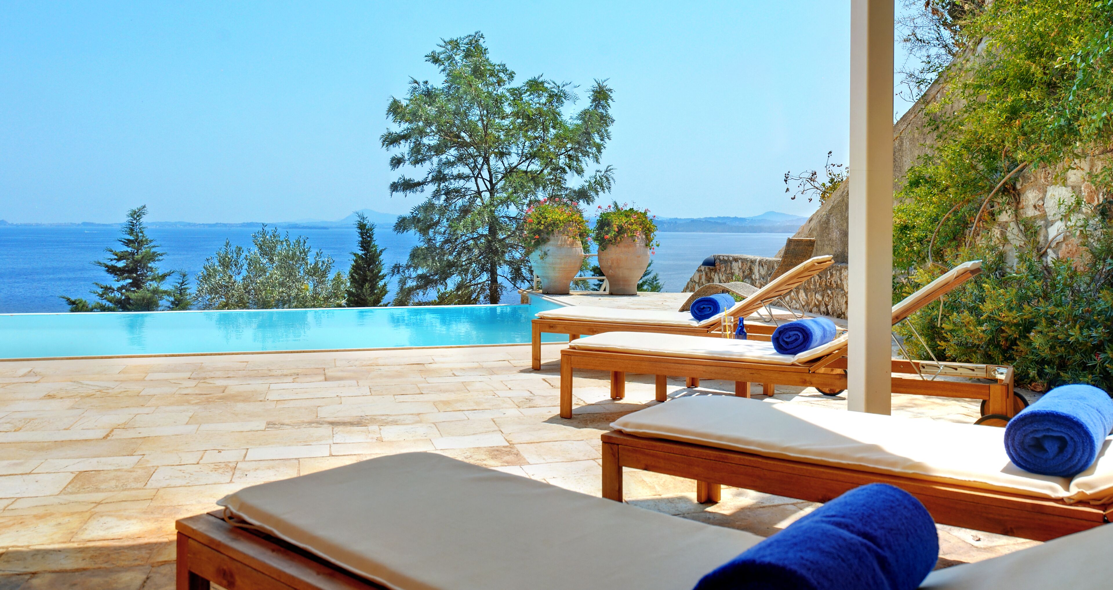 A poolside area with lounge chairs and a view of the sea.