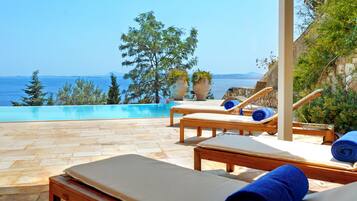 A poolside area with lounge chairs and a view of the sea.