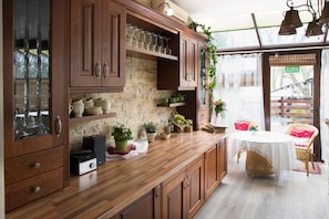 Una cocina con armarios de madera, pared de ladrillo y un comedor con sillas de mimbre.