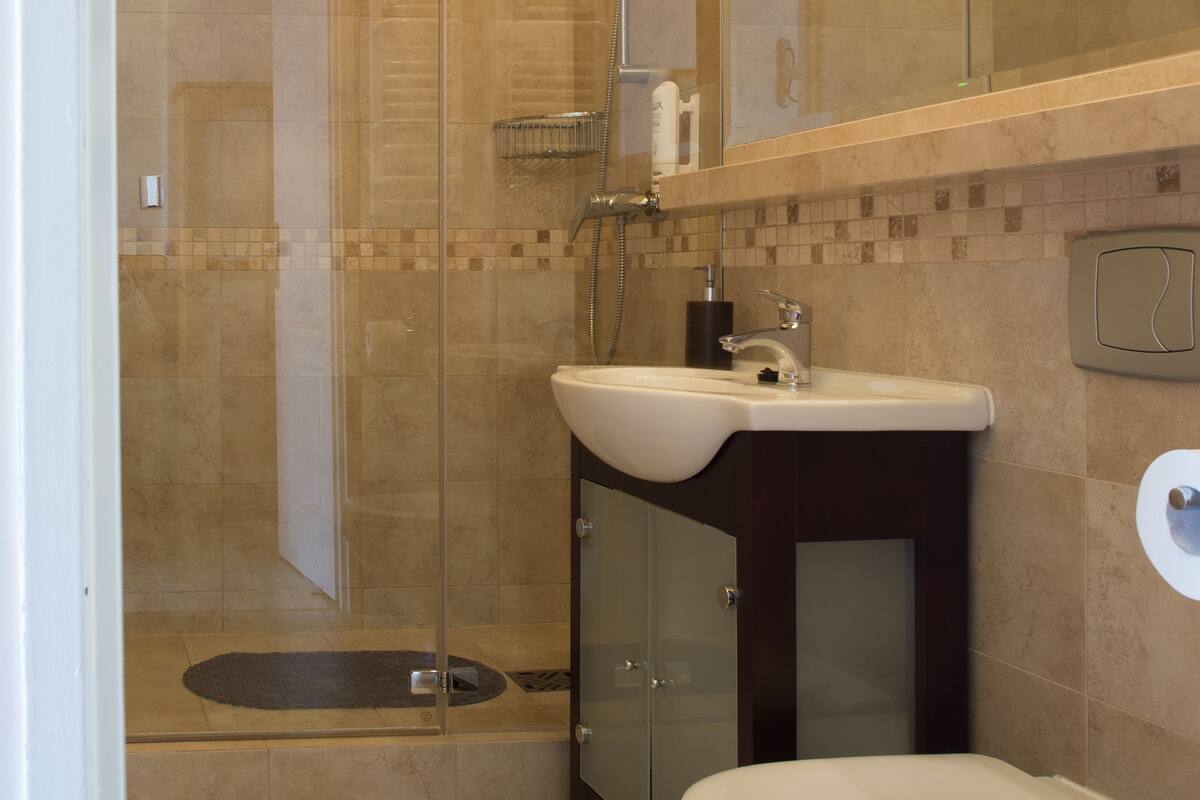 A modern bathroom with a glass-enclosed shower, a sink, and a toilet.