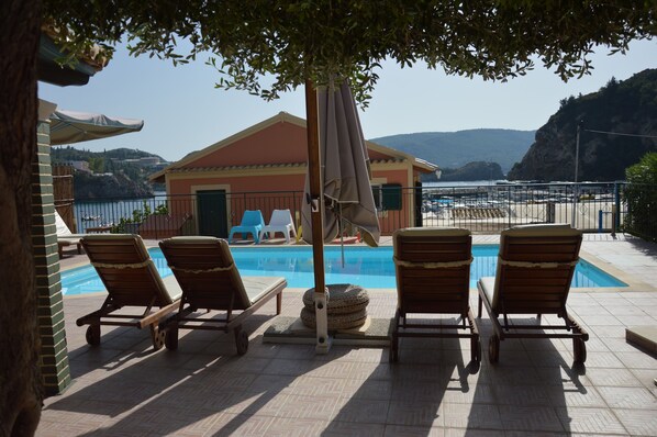 Una piscina al aire libre, sombrillas, sillones reclinables de piscina
