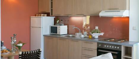 A compact kitchen with wooden cabinets, a microwave, a sink, and a stove.