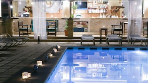 A poolside area with lounge chairs, candles, and a bar with shelves of bottles. - Govino Bay (Corfu)