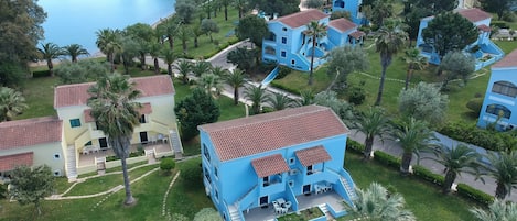A residential area with blue and yellow houses, a central blue house with a red roof, and a lake in the background.