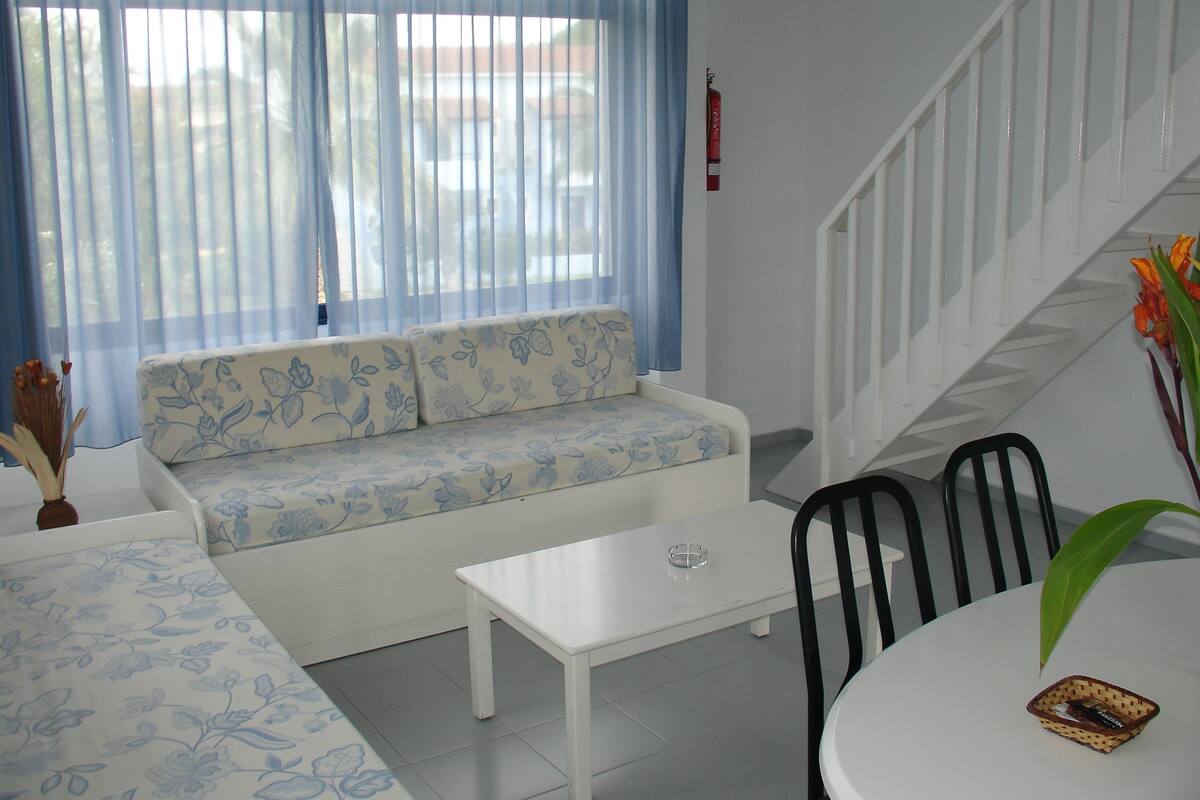 Una sala de estar con un sofá, una mesa de centro y una escalera.