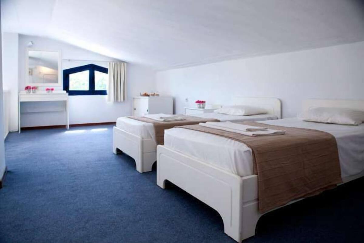 Una habitación de hotel con dos camas, un escritorio, un espejo y una ventana.