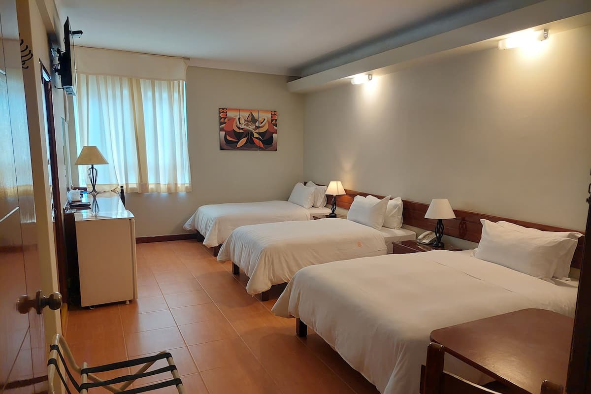 Hotellihuone, jossa on kaksi sänkyä, työpöytä, tuoli ja taulu seinällä.