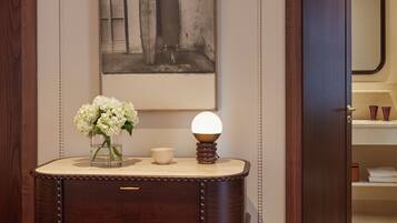 A wooden dresser with drawers and a vase of flowers, a framed picture on the wall, and a mirror in the background.