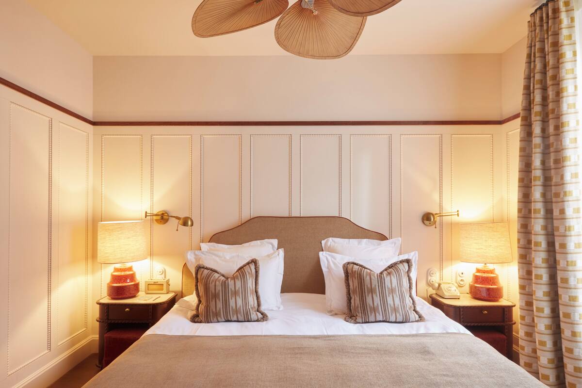 A hotel room with a large bed, two bedside tables with lamps, and a ceiling fan.