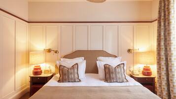 A hotel room with a large bed, two bedside tables with lamps, and a ceiling fan.