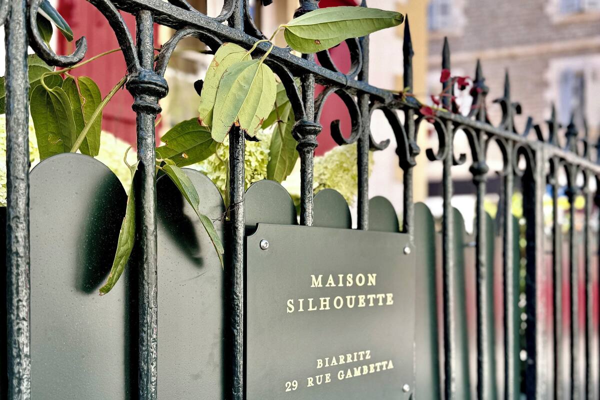 A metal fence with a sign that reads "MAISON SILHOUETTE BIARRITZ 29 RUE GAMBETTA."