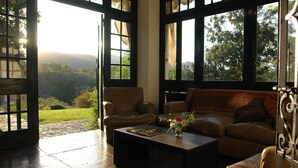 A spacious living room with a large window, a leather sofa, a coffee table, and a chair.