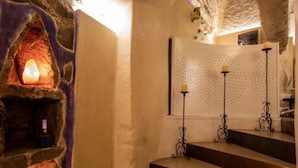Una escalera con un muro de piedra a un lado y un muro con diseño punteado y candelabros al otro.