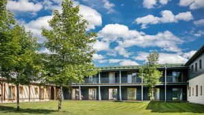 A modern building with multiple balconies, large windows, and a well-maintained lawn. - JUFA Hotel Erlaufsee (Mariazell)