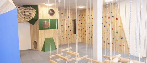 Un mur d’escalade avec des prises en bois et une zone protégée par un filet.