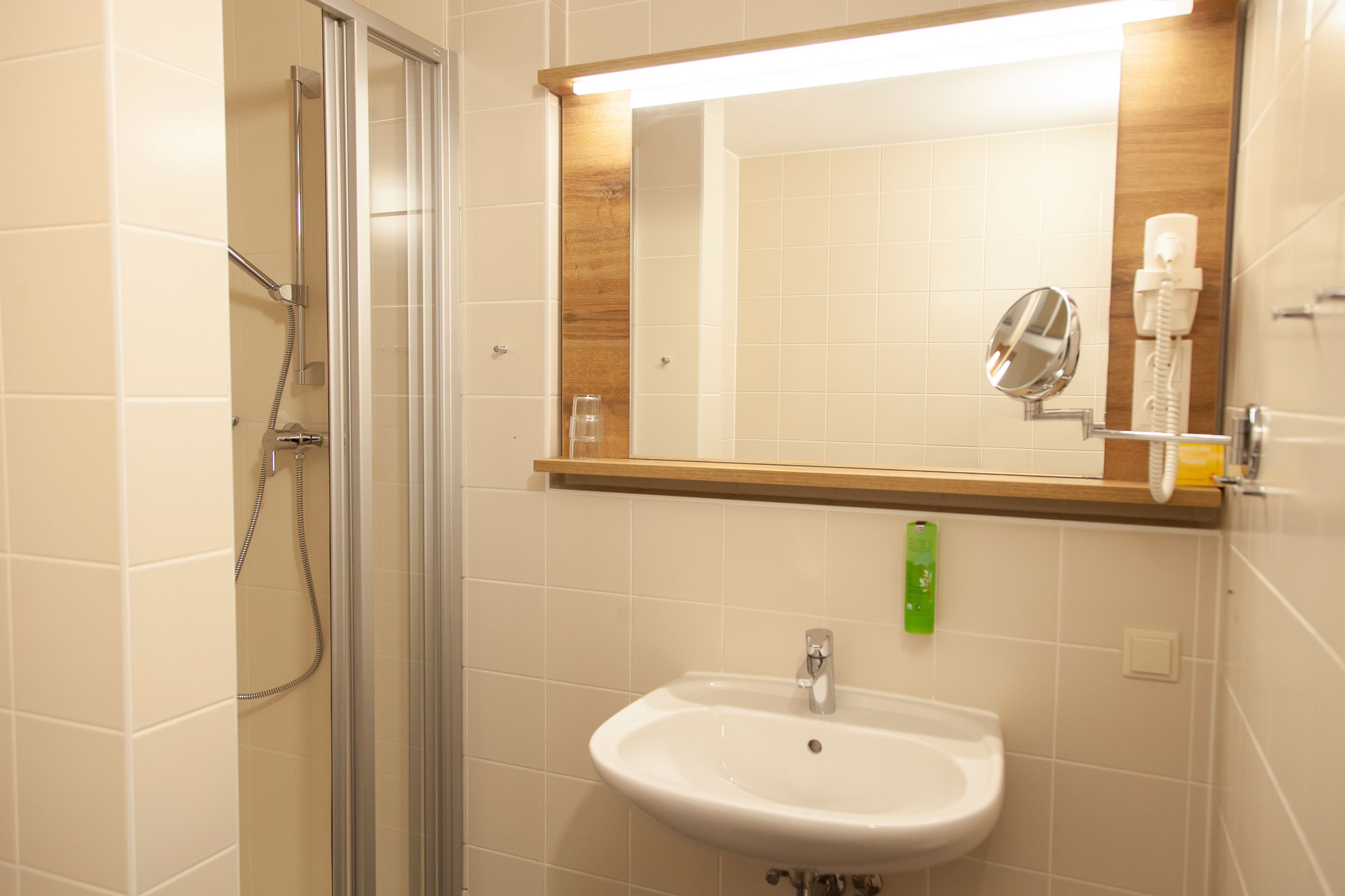 Un baño con cabina de ducha de vidrio, un lavabo blanco y un espejo encima.
